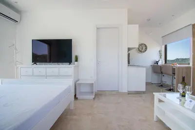 a white bedroom with a large bed and a tv at ''Aetheria'' Rooftop Resort with sea view in Kremasti