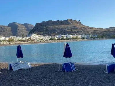 three beach chairs and umbrellas on the beach at Haraki Acqua e Sole Ground Floor House in Haraki