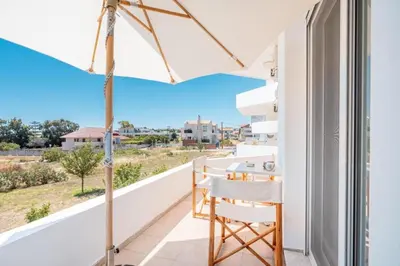 a balcony with white chairs and an umbrella at Elias Apartments with View in Rhodes Town