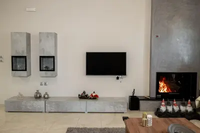 a living room with a fireplace and a tv on the wall at Mary Luxury House in Émbonas