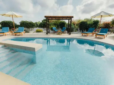 a swimming pool with blue chairs and a gazebo at Holiday Home Gennadi Dreams Ferienvilla by Interhome in Gennadi