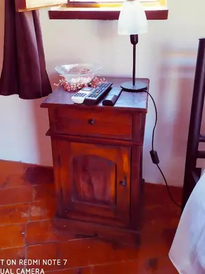 a night stand with a lamp and remote controls on it at Villa Chrysodimi in Halki