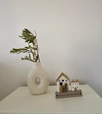 a white vase with a plant and a house on a table at Ivory Serenity in Theologos