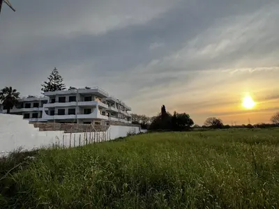 a house in a field with the sunset in the background at Ivory Serenity in Theologos