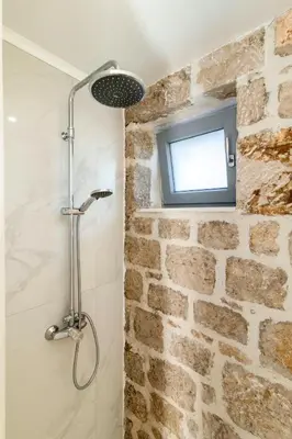 a bathroom with a shower with a tv on a brick wall at Kastro - Country Villa in Rhodes Town