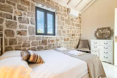 a stone walled bedroom with a bed and a window at Kastro - Country Villa in Rhodes Town