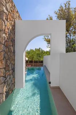 an infinity pool with a stone wall and blue water at Avaton Boutique Suites in Vrachonisída touArchangélou