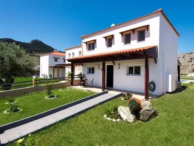 a white house with a green lawn in front of it at Holiday Home Haus in Kolympia mit Garten und Bergblick by Interhome in Kolimbia