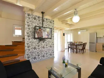 a living room with a tv on a wall at Holiday Home Haus in Kolympia mit Garten und Bergblick by Interhome in Kolimbia