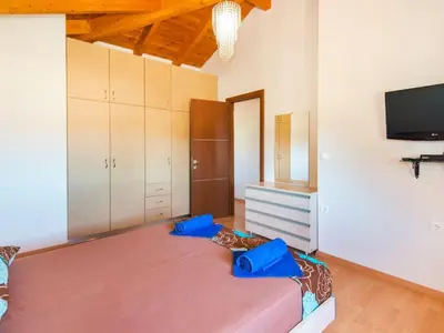 a bedroom with a large bed with a tv on the wall at Holiday Home Haus in Kolympia mit Parkplatz und Bergblick by Interhome in Kolimbia