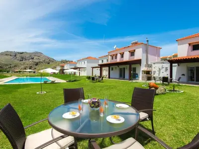 a patio with a table and chairs and a pool at Holiday Home Haus in Kolympia mit Parkplatz und Bergblick by Interhome in Kolimbia