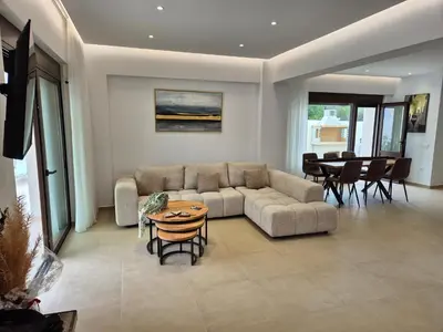 a living room with a couch and a table at Luxe nieuwe villa met zwembad in Kalithies