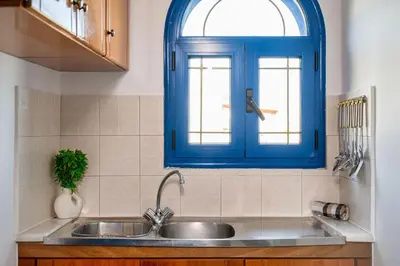 a kitchen with a sink and a blue window at Anna's view Stegna in Vrachonisída touArchangélou