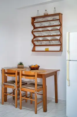 a dining room table with chairs and a refrigerator at Anna's view Stegna in Vrachonisída touArchangélou