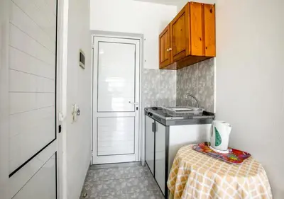 a small kitchen with a sink and a table at Paras Sun Hotel & Apartments in Ialyssos