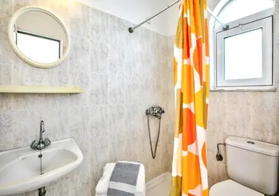 a bathroom with a sink and a toilet and a mirror at Paras Sun Hotel & Apartments in Ialyssos