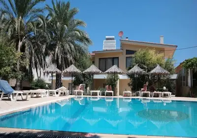 a swimming pool with chairs and umbrellas in front of a building at Paras Sun Hotel & Apartments in Ialyssos
