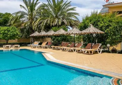 a swimming pool with lounge chairs and umbrellas at Paras Sun Hotel & Apartments in Ialyssos