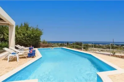 a swimming pool with two people sitting in chairs next to it at Villa Nicole Gennadi in Gennadi