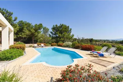 a swimming pool with two chairs and a house at Villa Phoebe Gennadi in Gennadi