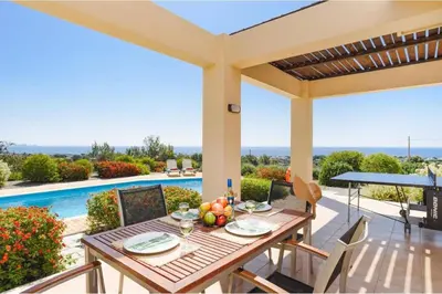 a table and chairs on a patio with a pool at Villa Phoebe Gennadi in Gennadi