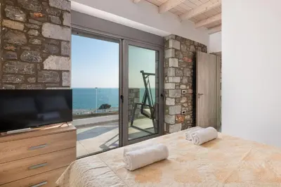 a bedroom with a large window with a view of the ocean at Pefkos Sea Serenity Villas in Líndos