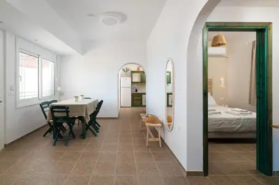 a dining room with a table and chairs and a bed at Oniro Beach House in Archangelos