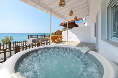 a hot tub on a patio with the ocean in the background at Oniro Beach House in Archangelos