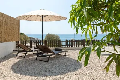 a patio with two chairs and an umbrella at Oniro Beach House in Archangelos