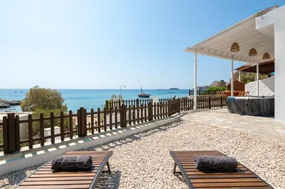 two benches on a patio with the ocean in the background at Oniro Beach House in Archangelos