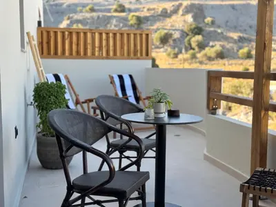 a table and chairs on a balcony with a view at Yucca Calma in Líndos
