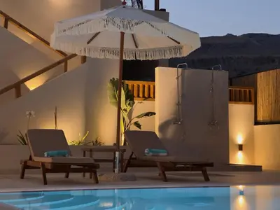 two chairs and an umbrella next to a swimming pool at Yucca Calma in Líndos