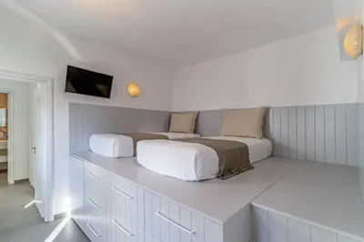 a bedroom with two beds and a tv on the wall at Lindos 4 me Villa in Líndos
