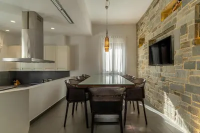 a kitchen with a dining table and a brick wall at Lindos 4 me Villa in Líndos