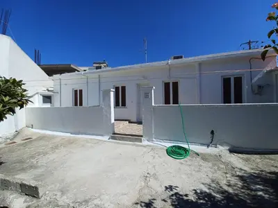 a white house with a green hose in front of it at Pension Annoula in Archangelos