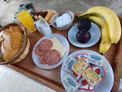 a wooden table topped with plates of breakfast foods and a banana at Pension Annoula in Archangelos