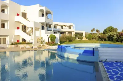 a swimming pool in front of a building at Hercules Plus in Faliraki