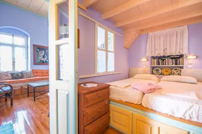 a bedroom with purple walls and a bed with a dresser at Symi Traditional Appartment in Symi