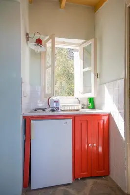 a red and white kitchen with a sink and a window at Symi Traditional Appartment in Symi