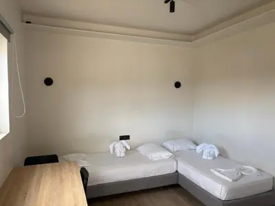 a white room with two beds and a wooden table at Barbie II in Ialyssos