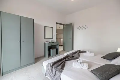 a white bedroom with two beds and a bathroom at Rhodes Archaggelos Nests - Fully Equipped Getaways in Archangelos