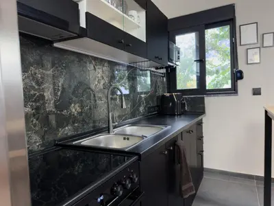 a kitchen with black cabinets and a sink at Kálos Housing - Adults Only in Kolimbia