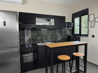 a kitchen with black cabinets and a wooden counter top at Kálos Housing - Adults Only in Kolimbia