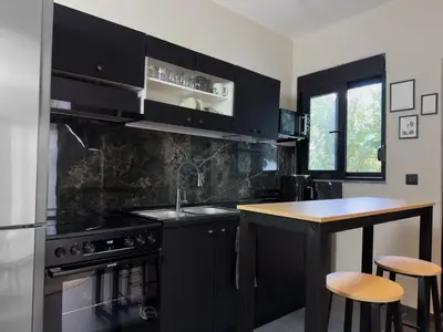 a kitchen with black cabinets and a counter with stools at Kálos Housing - Adults Only in Kolimbia