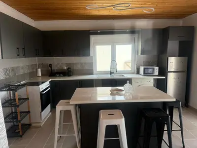 a kitchen with a sink and a counter with stools at Little Paradis in Archangelos