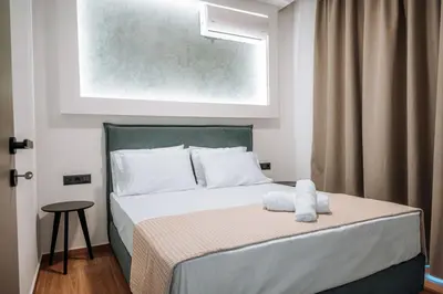 a bedroom with a bed with white sheets and a window at ILIADA Boutique Rooms in Faliraki