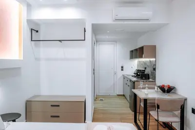 a kitchen with white walls and a table and chairs at ILIADA Boutique Rooms in Faliraki