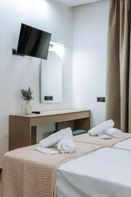 a hotel room with two beds with a tv on the wall at ILIADA Boutique Rooms in Faliraki