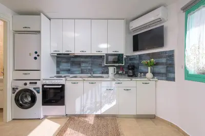 a white kitchen with a sink and a dishwasher at Malonas Village house in Malona Village