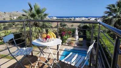 a table with a bowl of fruit and two chairs on a balcony at Villa with 2 bedrooms - 2 bathrooms - Private pool in Haraki